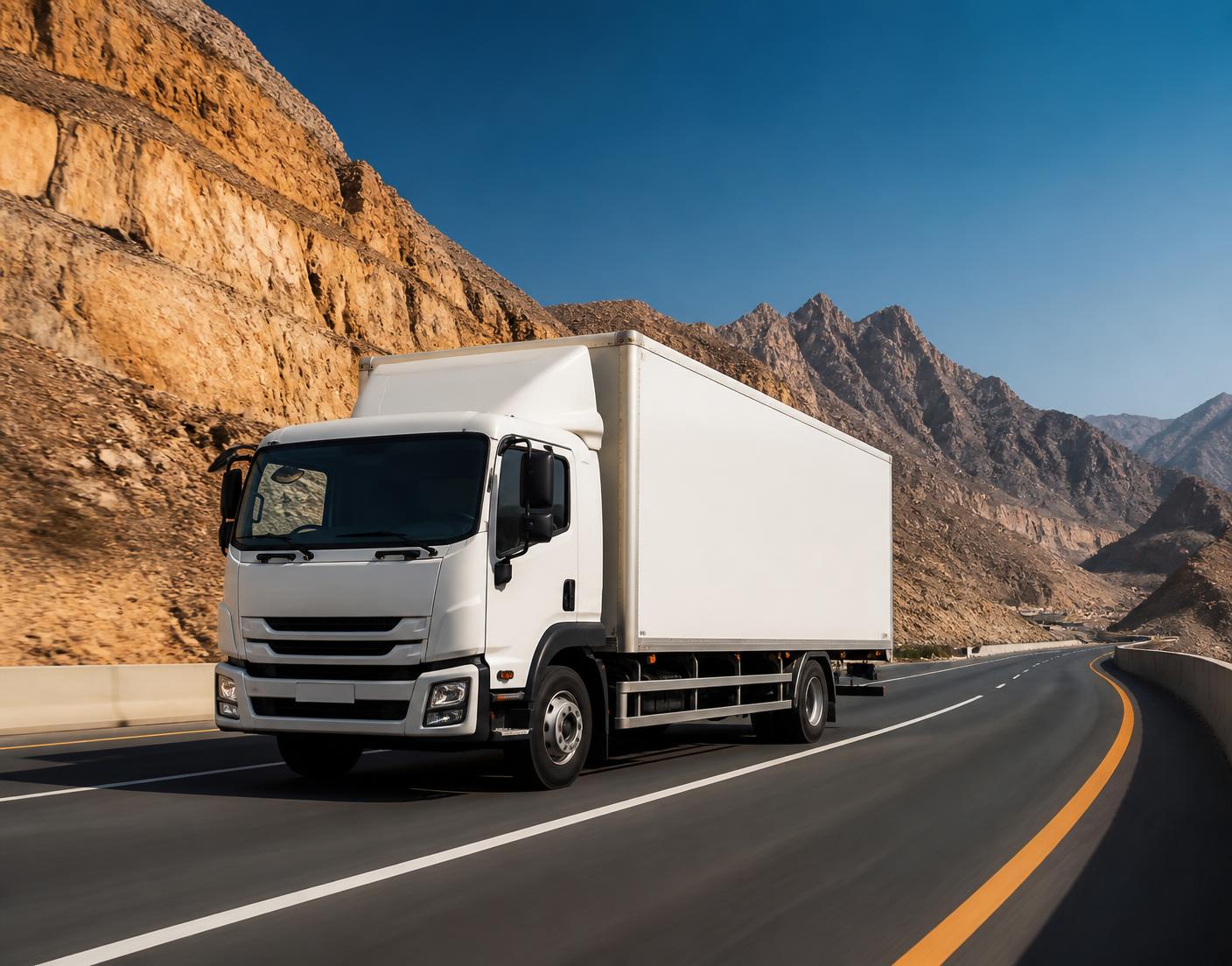 White cargo truck driving through the Hajar mountains